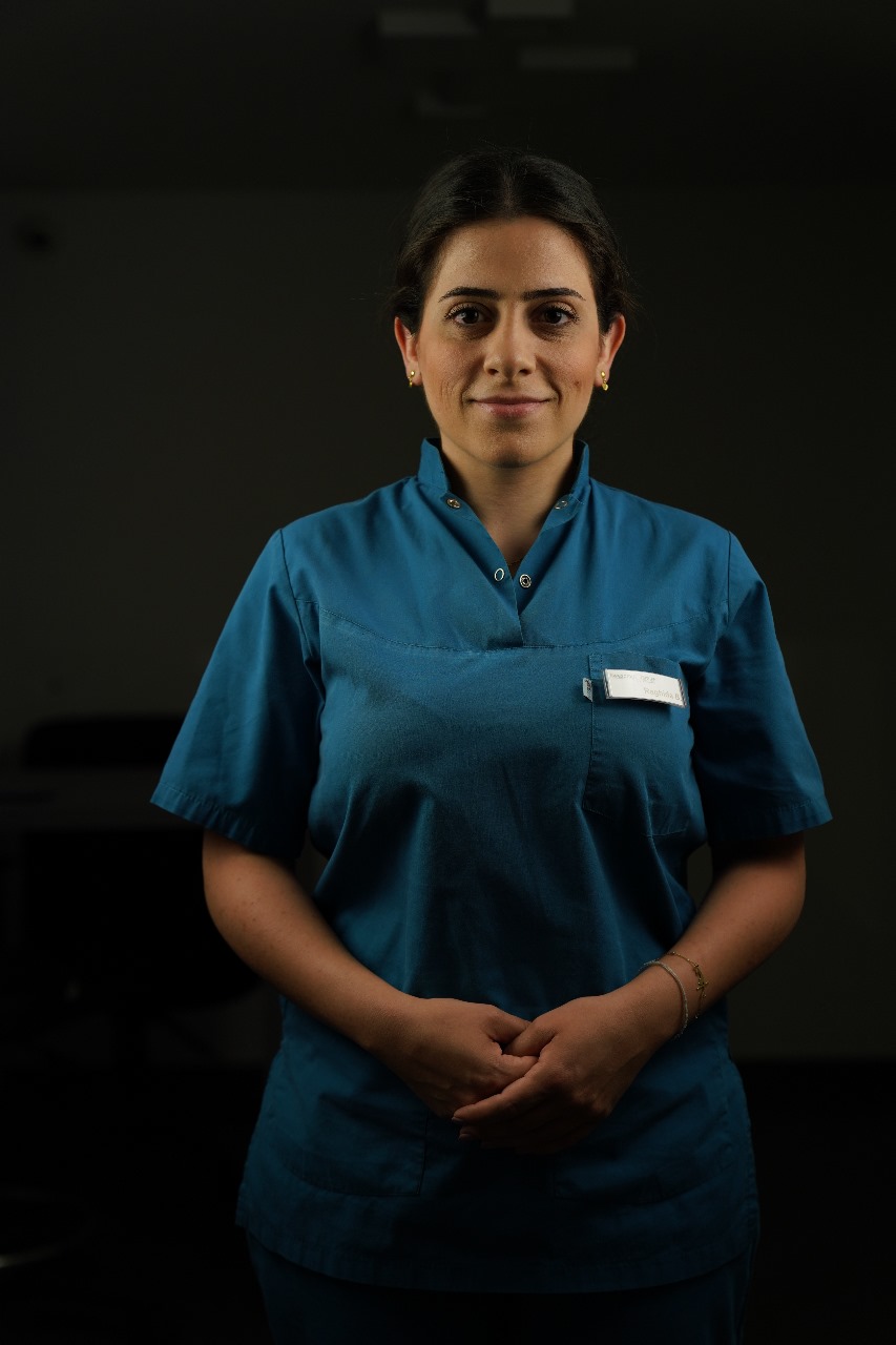Team member in teal scrubs, name unconfirmed